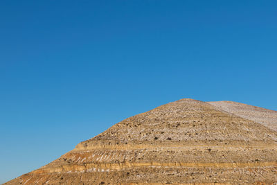 Low angle view of historical egyptian pyramid against blue sky