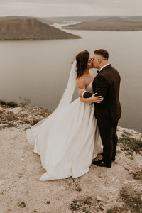 Portrait of bride and bridegroom standing on sand at beach