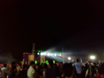 Crowd at music concert against sky at night