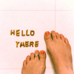 Low section of woman with hello there text on tiled floor