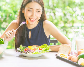 Smiling young woman having breakfast at table