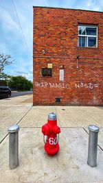 Red fire hydrant on building against sky