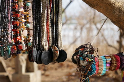 Close-up of various pendants and bracelets hanging from tree for sale