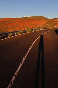 Shadow of man on road against clear sky