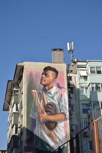 Low angle view of man standing against building against clear sky