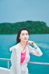 Portrait of young woman standing against blue sky