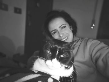 Portrait of smiling woman with cat at home