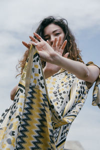 Low angle view of woman with arms raised against sky