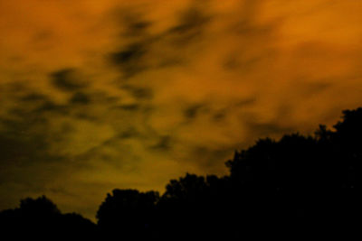 Silhouette of trees against cloudy sky