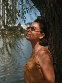 Side view of smiling young woman against trees