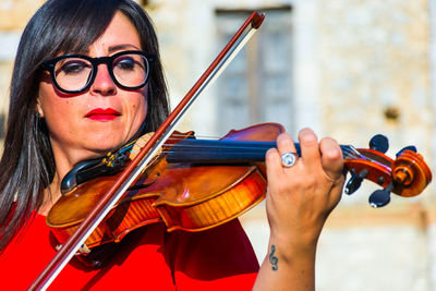 Close-up of woman playing violin in city