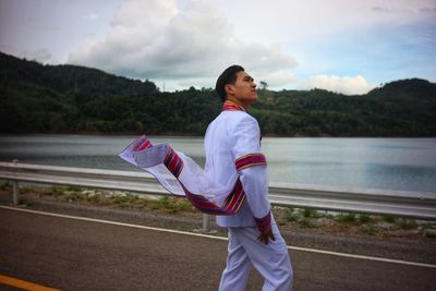 Full length side view of man standing by lake against sky