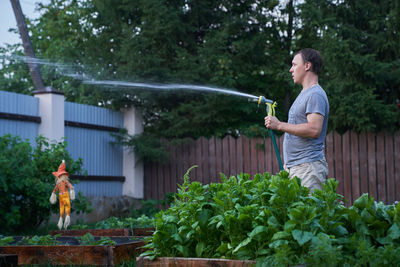 Jet spraying of water in daylight. a man watering plants in the garden. gardening and hobby concept.