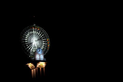 Illuminated ferris wheel against black background