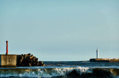 Lighthouse by sea against clear sky