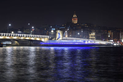 Illuminated bridge over bay against sky at night