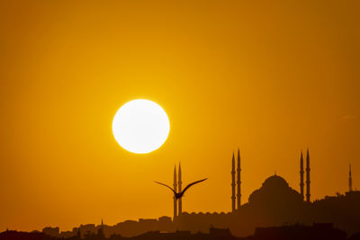 Silhouette built structure against orange sky