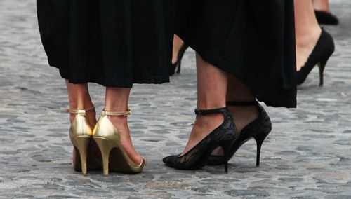 Low section of women wearing high heels on footpath