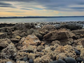 Rocks on beach against sky during sunset