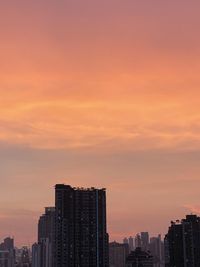 Modern buildings against sky during sunset