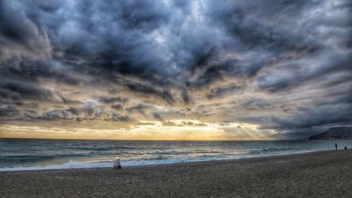 Scenic view of beach against dramatic sky