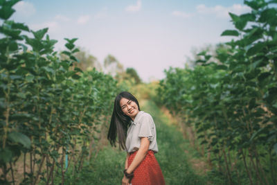 Young woman standing against trees