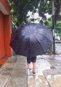 Full length of woman standing on footpath during rainy season