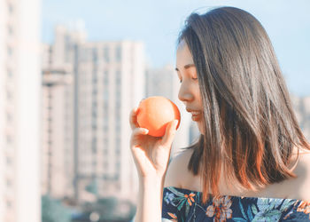 Woman holding orange in city