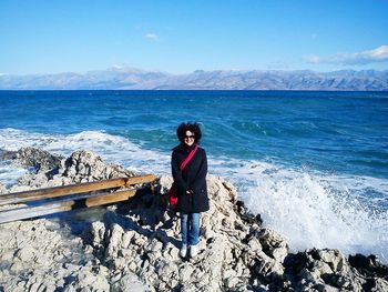 Full length of young woman standing on rock formation at beach