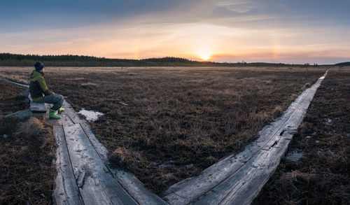 Man on field against sky during sunset