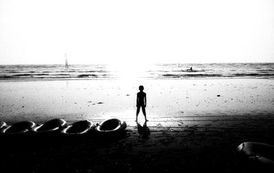 Rear view of people on beach against clear sky