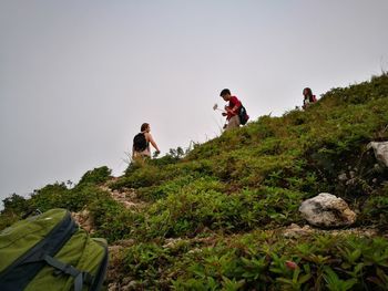 Friends on mountain against clear sky