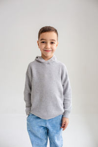 Portrait of smiling boy standing against white background