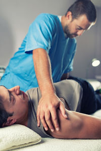 Man receiving massage therapy while lying on bed