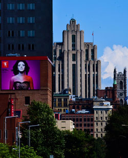 Statue by buildings in city against sky