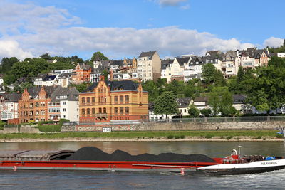 Buildings by river against sky in city