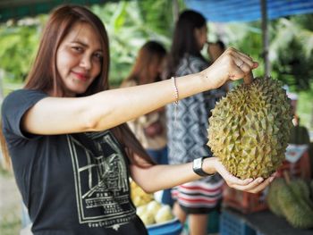 Portrait of smiling woman holding durian