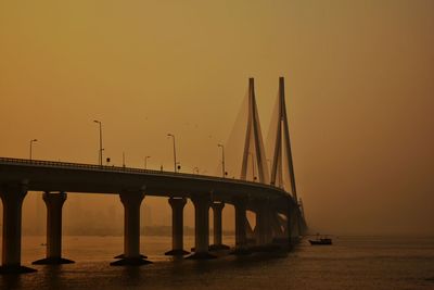 Bridge over sea against clear sky during sunset