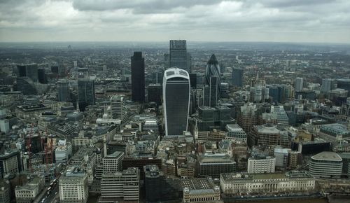 High angle view of city buildings against cloudy sky