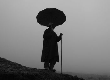 Silhouette of woman holding umbrella