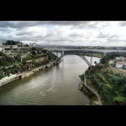 Bridge over river against cloudy sky