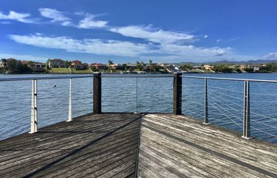 Wooden pier over sea against blue sky