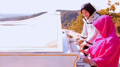 Women playing piano on sunny day