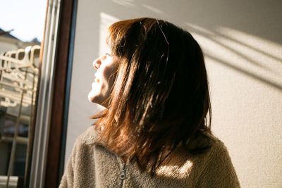 Woman looking through window at home