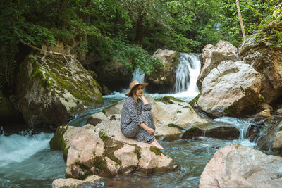 Young woman with hat enjoying in nature, relaxing and thinking in beautiful water oasis