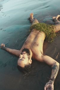 High angle view of shirtless man lying in water