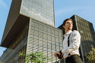 Low angle view of man standing against modern buildings