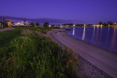 River by illuminated city against sky at dusk