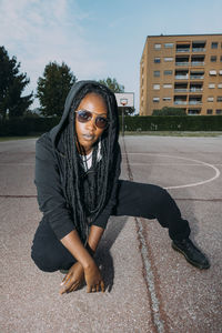 Woman with hooded shirt crouching at sports court