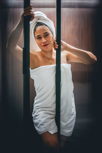 Portrait of woman wrapped in towel while standing at home